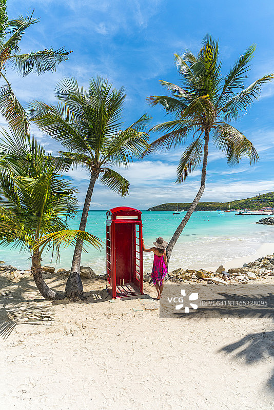 在安提瓜迪克森湾锡伯尼海滩的电话亭旁的女人图片素材
