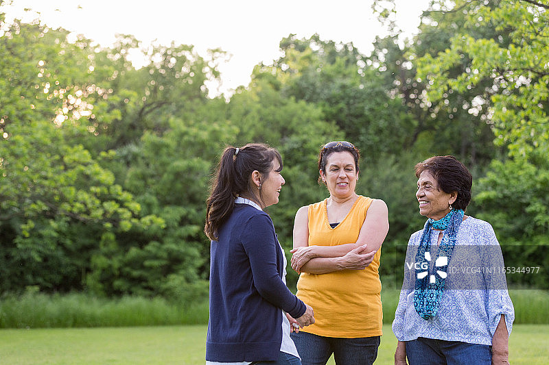 女儿们在公园里和年长的母亲站着交谈图片素材