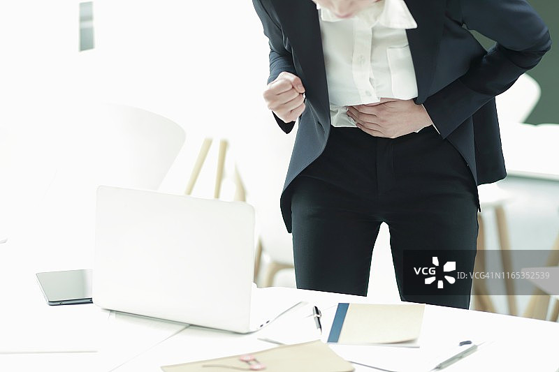 在办公室里肚子疼的女商人图片素材