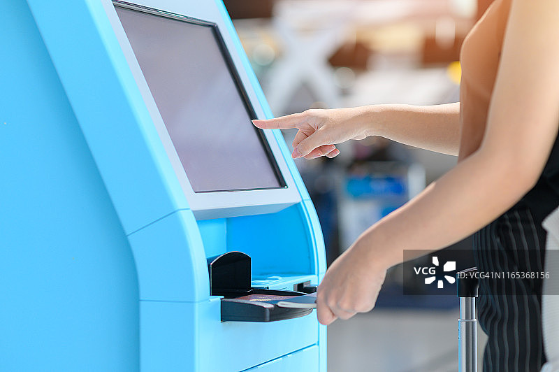 女人在机场通过机器办理登机手续图片素材