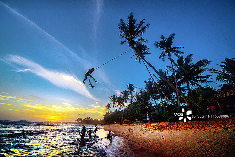 男孩在斯里兰卡乌纳瓦图纳海滩上荡绳子图片素材