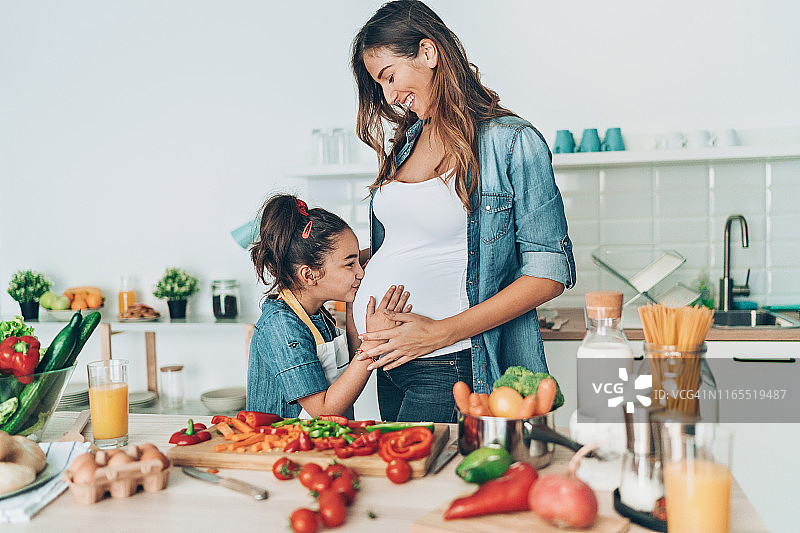 亲吻怀孕妈妈的小女孩图片素材