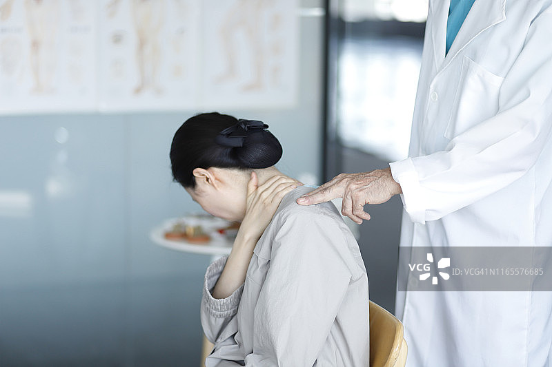 东方医学医生检查患者的肩部疼痛图片素材
