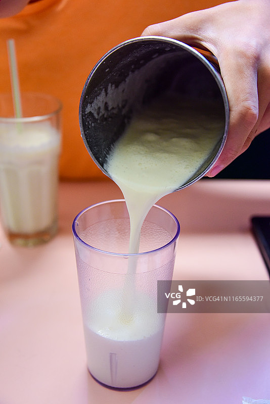 将香草奶昔从摇杯倒入玻璃杯中图片素材