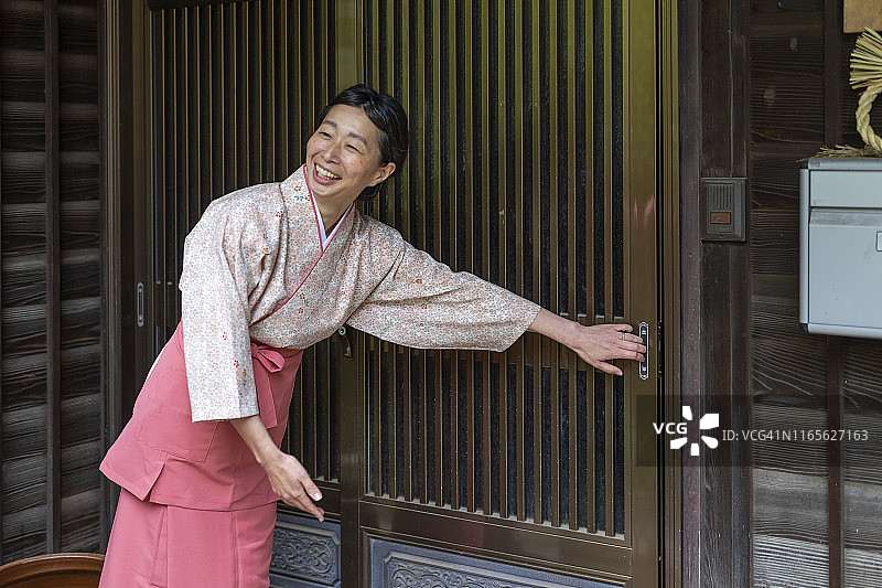 身着传统服饰的日本女人向旅馆游客鞠躬图片素材