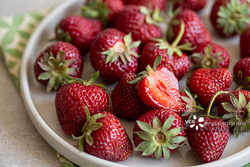 浅色背景的泥盘中成熟多汁的草莓，带有复制空间图片素材