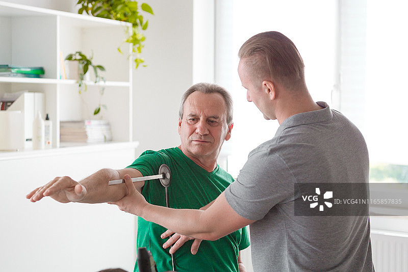 理疗师用测角器检查患者的肩膀图片素材