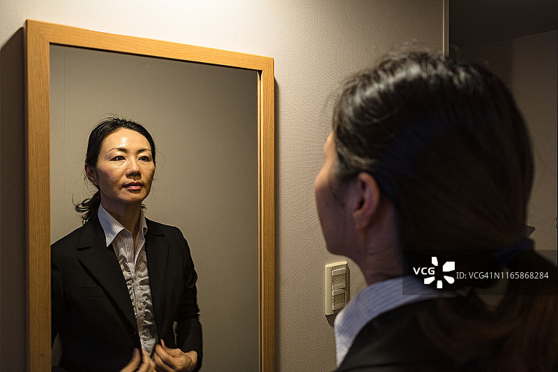 女商人在黑暗的房间里照镜子图片素材