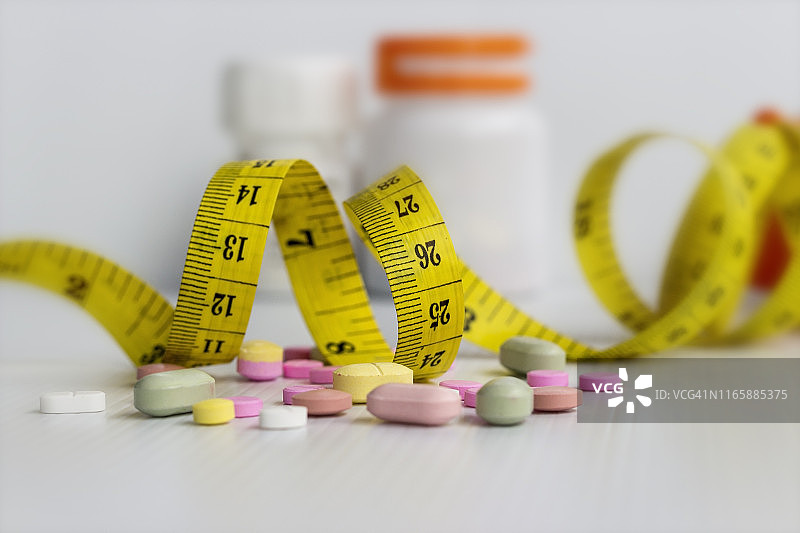 饮食概念；服用药丸减肥，白色背景上的药丸，对健康有害图片素材
