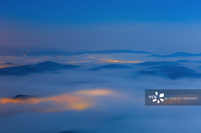 蓝色光芒和神奇雾气覆盖山脉的山峰长曝光图片素材