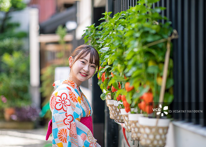 身穿浴衣的年轻女人站在有冬樱花的街道上图片素材