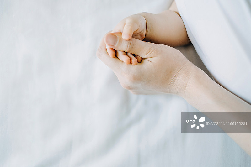 母亲握着婴儿的手的特写，白色背景图片素材