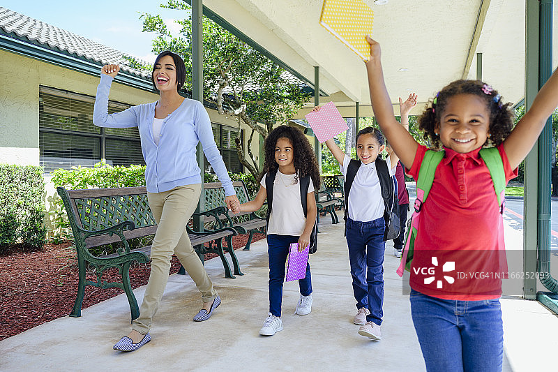 积极的西班牙裔教师和学生在户外散步图片素材