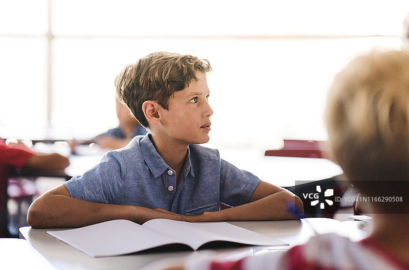 男孩在学校的课桌旁学习图片素材