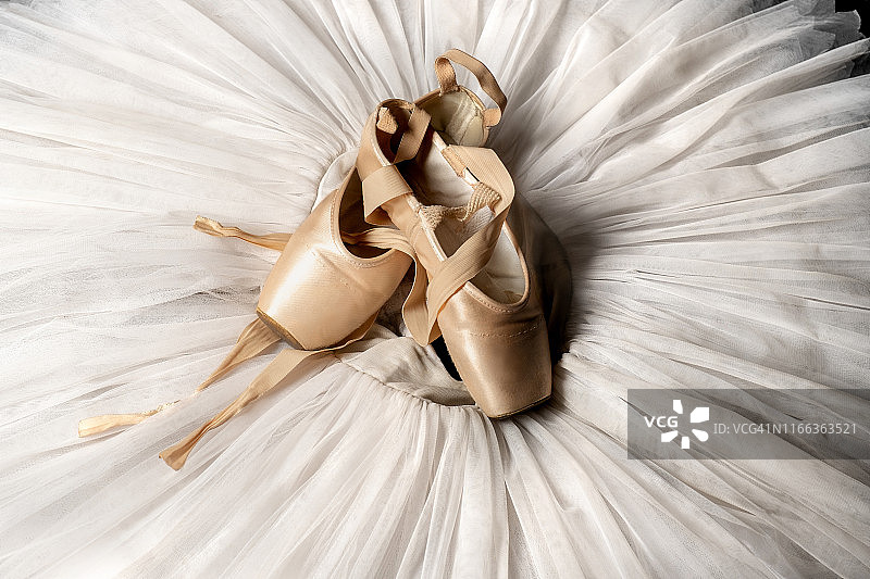 足尖鞋：舞蹈工作室中白色芭蕾舞裙上的桃色芭蕾舞鞋与缎带，芭蕾舞学校广告，专业芭蕾舞演员服装图片素材