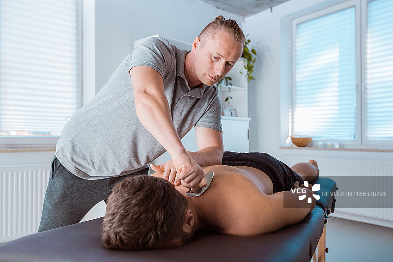 专业理疗师用工具进行背部按摩图片素材