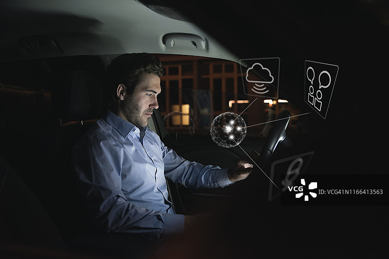 在夜晚的车中使用设备，周围环绕着互联网符号的商人图片素材