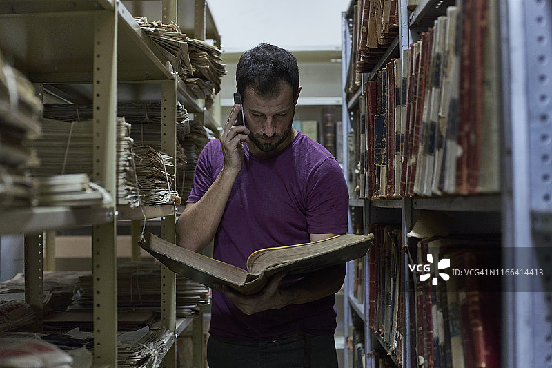 在书架中看旧书的打电话的男人，国家图书馆，马普托，莫桑比克图片素材