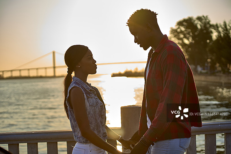 年轻情侣在日落时分手牵手图片素材