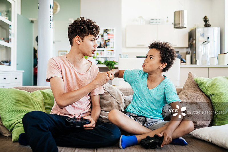 两兄弟玩电脑游戏时互相击拳图片素材