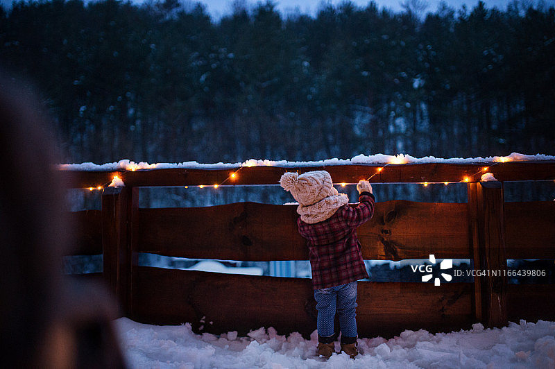 冬天户外小女孩站在露台上看雪的背影图片素材