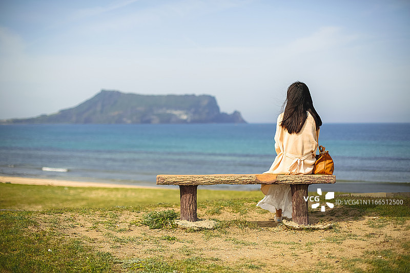 年轻女人坐在韩国济州岛的城山日出峰前图片素材
