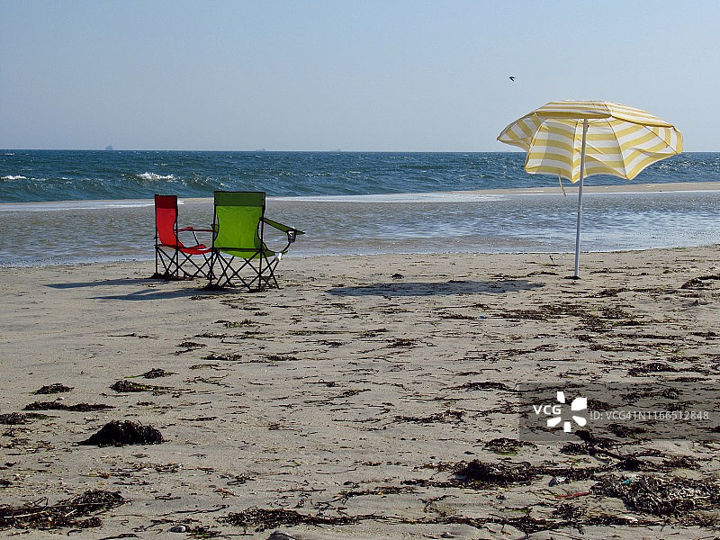 夏季水边沙滩上的两把沙滩椅和一把阳伞图片素材