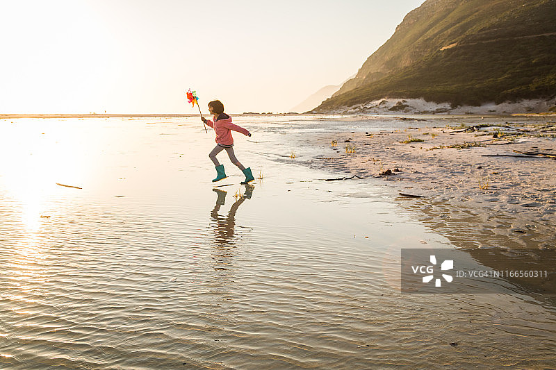 在海滩上玩风车玩具的混血女孩图片素材