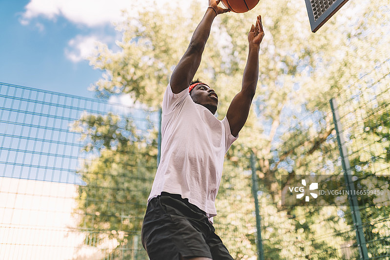 年轻男人用篮球跳投图片素材