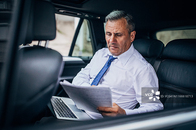 政治家在汽车后座准备演讲稿图片素材