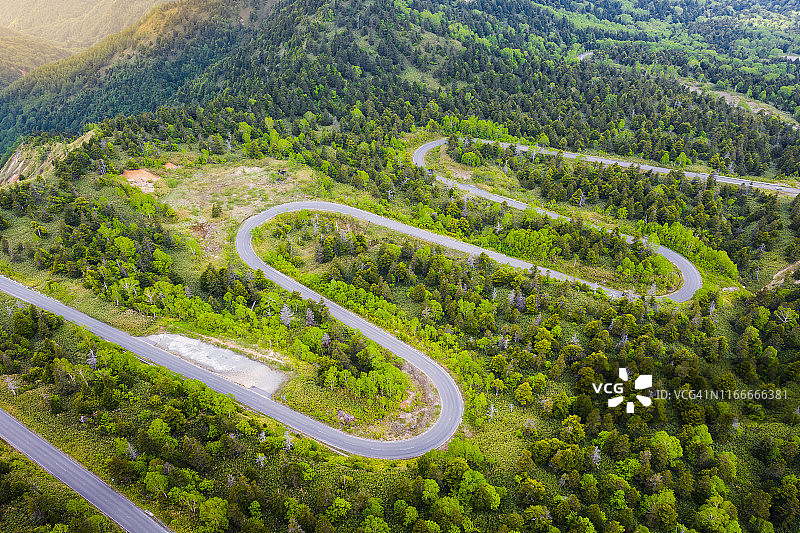 夏季山间绿林弯曲道路航拍视角图片素材