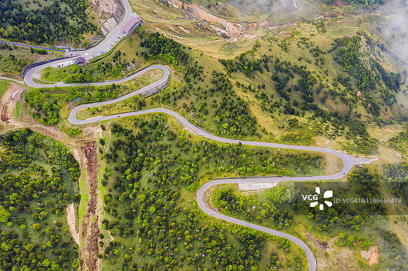 夏季山间绿林弯曲道路航拍视角图片素材