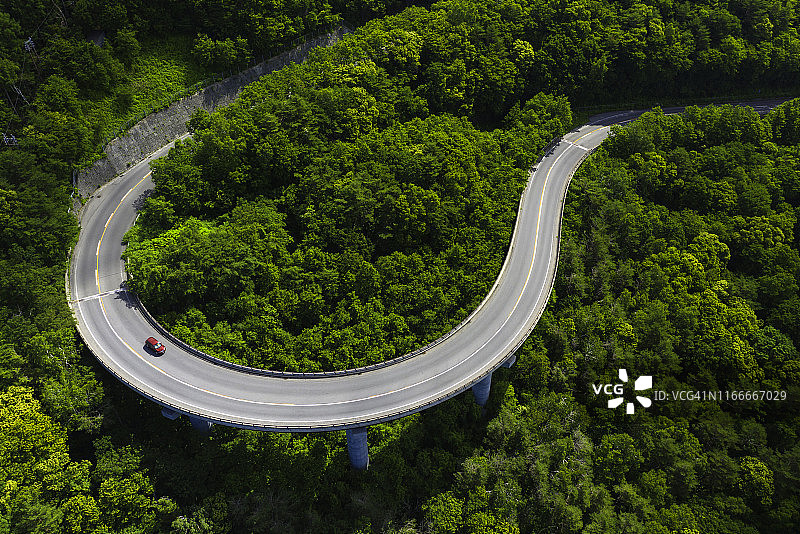 夏季山间绿林弯曲道路航拍视角图片素材