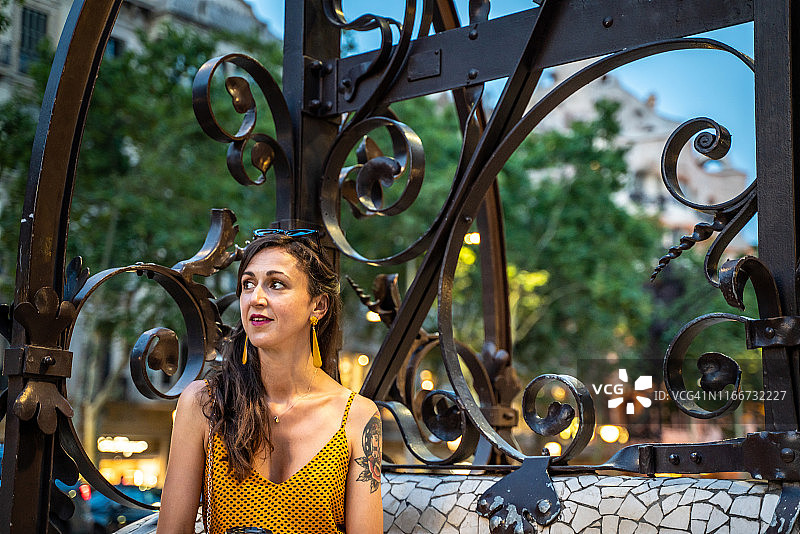 坐在巴塞罗那高迪设计的长椅上的美丽女人图片素材