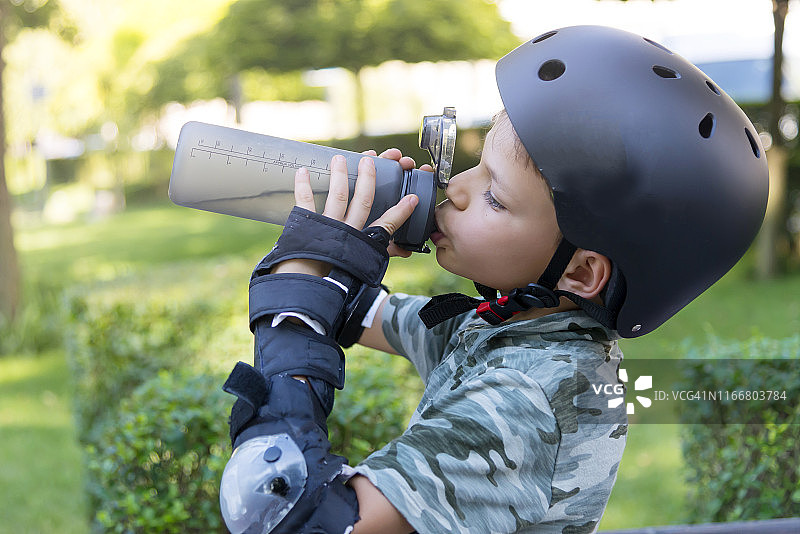 戴滑板头盔的孩子喝水图片素材