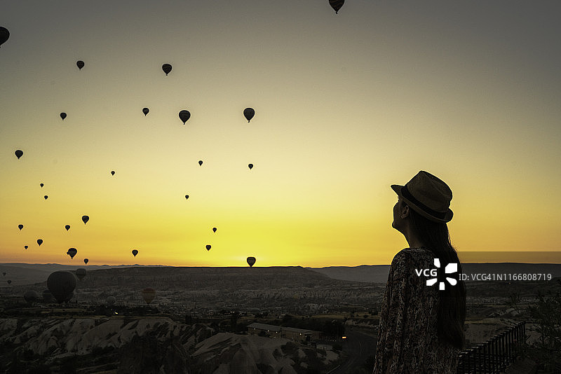 日落时看气球的青年女子背影图片素材