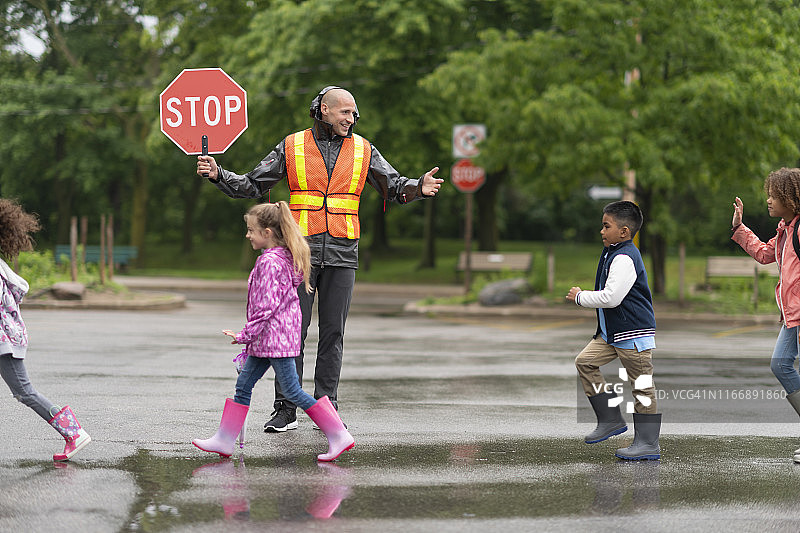 在交通协管员的帮助下，小学生们过马路图片素材