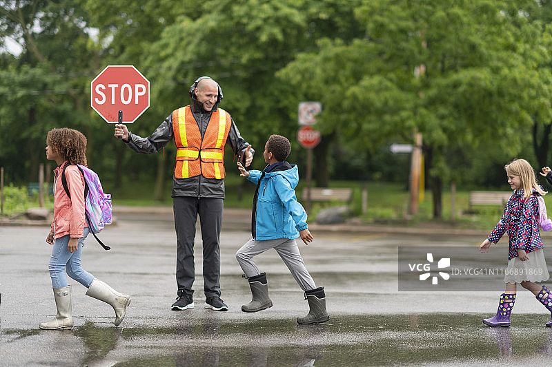 微笑的交通协管员帮助学生安全过马路图片素材