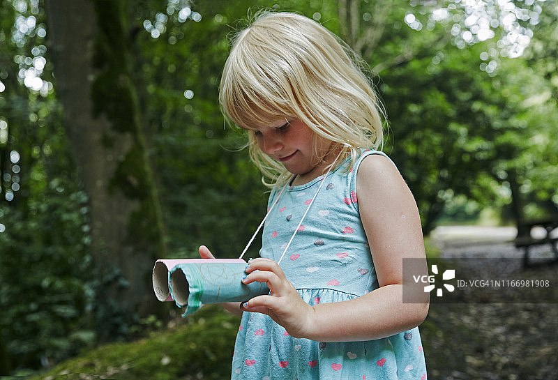 在森林里看自制玩具望远镜的四岁女孩图片素材
