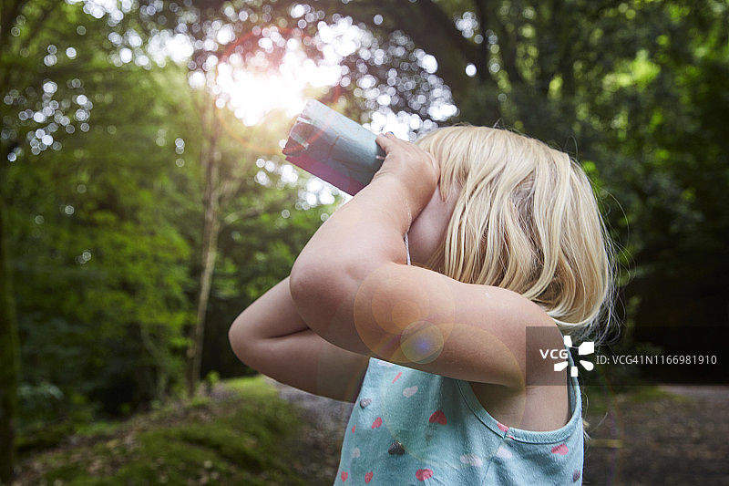 四岁女孩在森林里用自制玩具双筒望远镜观看图片素材
