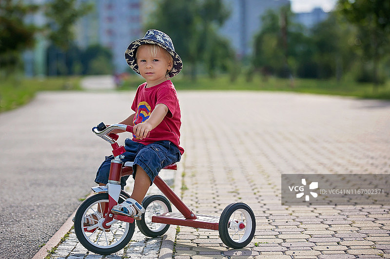 夏天在公园里骑三轮车的可爱幼儿男孩图片素材