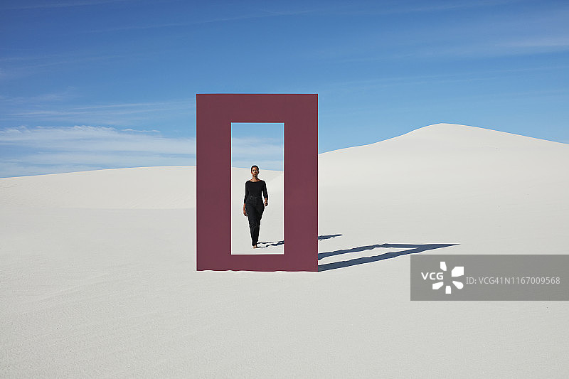 年轻女子走向白色沙丘上的门框图片素材