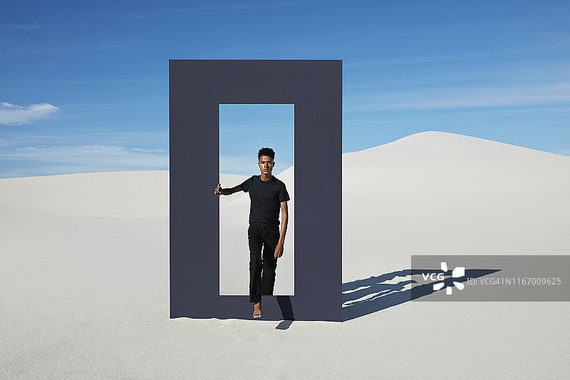 年轻男子走过沙漠门框的肖像图片素材