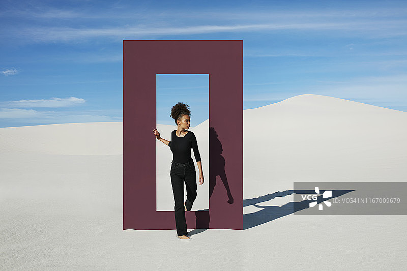 年轻时尚模特在沙漠中走过门框图片素材