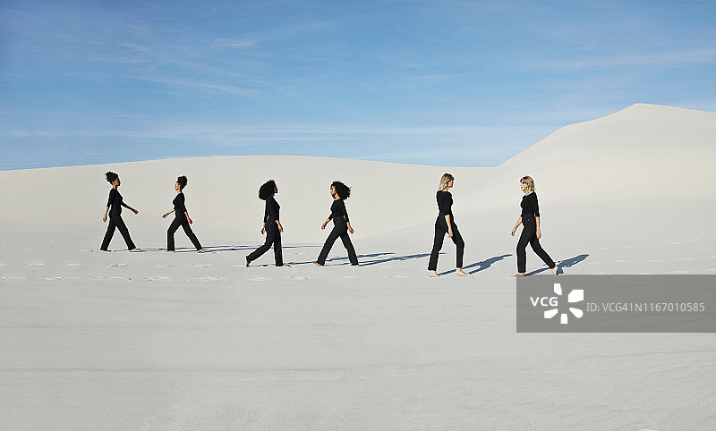 白色沙漠上对着蓝天走秀的女性模特影像图片素材