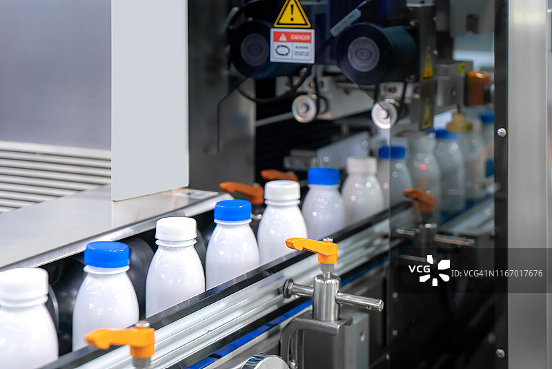 工业用贴标机上的瓶子移动，在传送带系统上传输透明瓶子图片素材