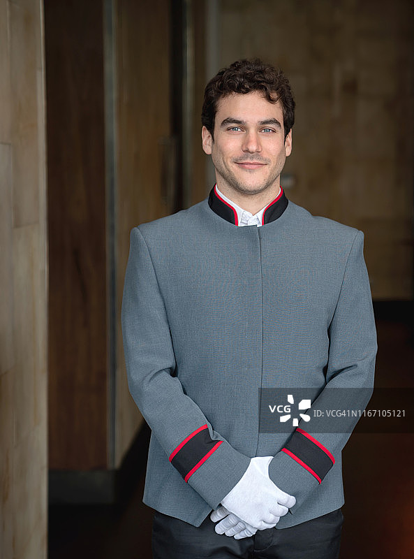 在酒店接待处面对镜头微笑的年轻英俊的行李员图片素材