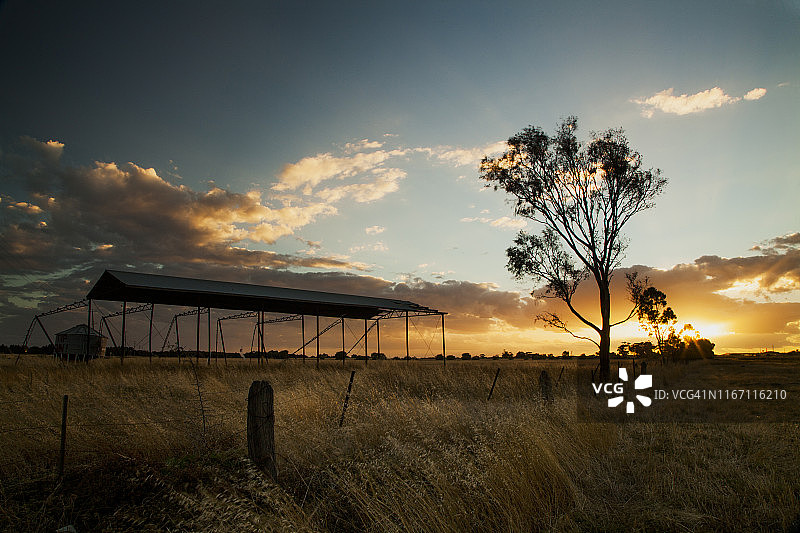 墨尔本Werribee的日落时分，土路旁的干草棚和水箱图片素材