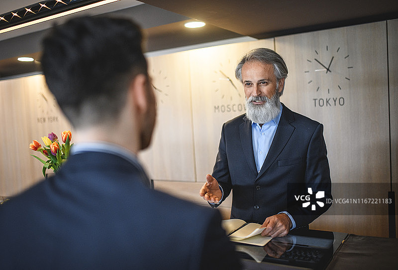 彬彬有礼的酒店接待员协助商人图片素材