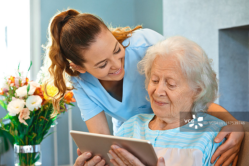 护士用平板电脑看望老年妇女图片素材